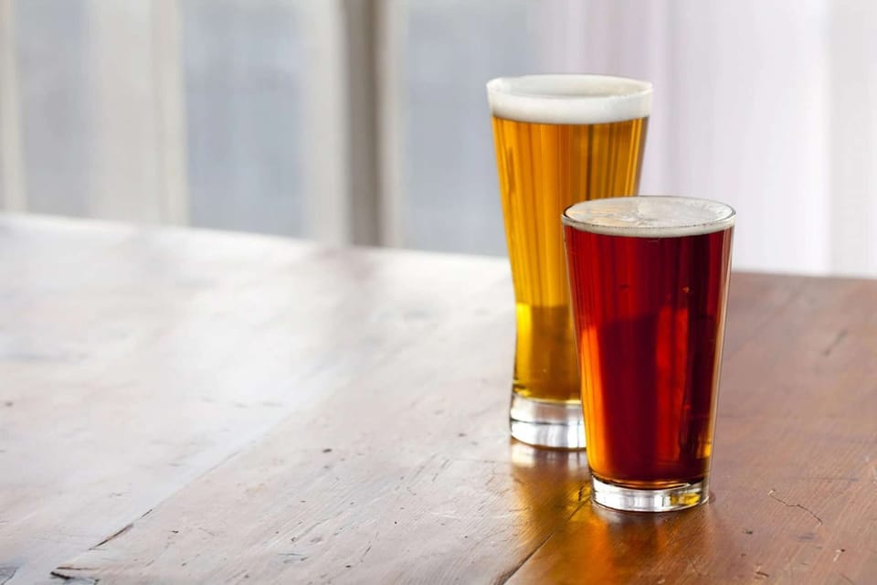 Two tall glasses of beer on wood table