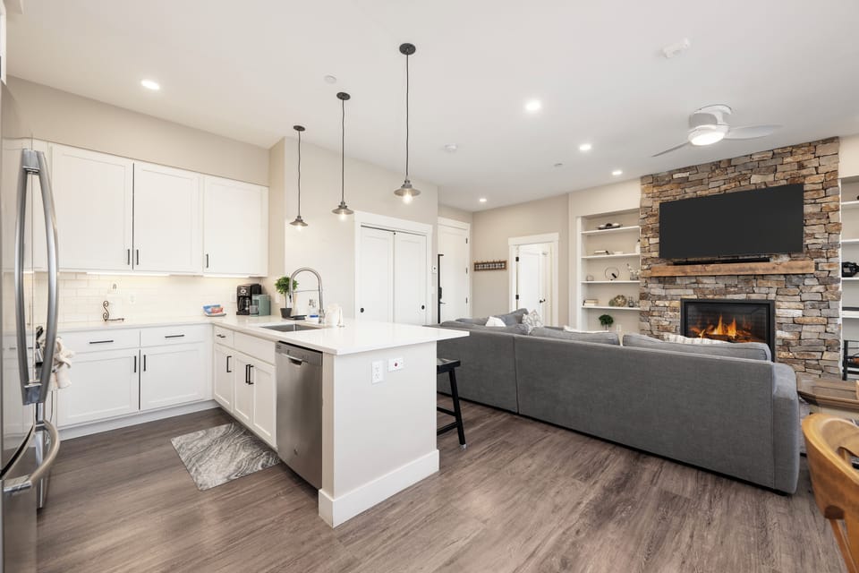Unwind in this stunning open-plan space where your modern kitchen flows into a cozy living area with stone fireplace.