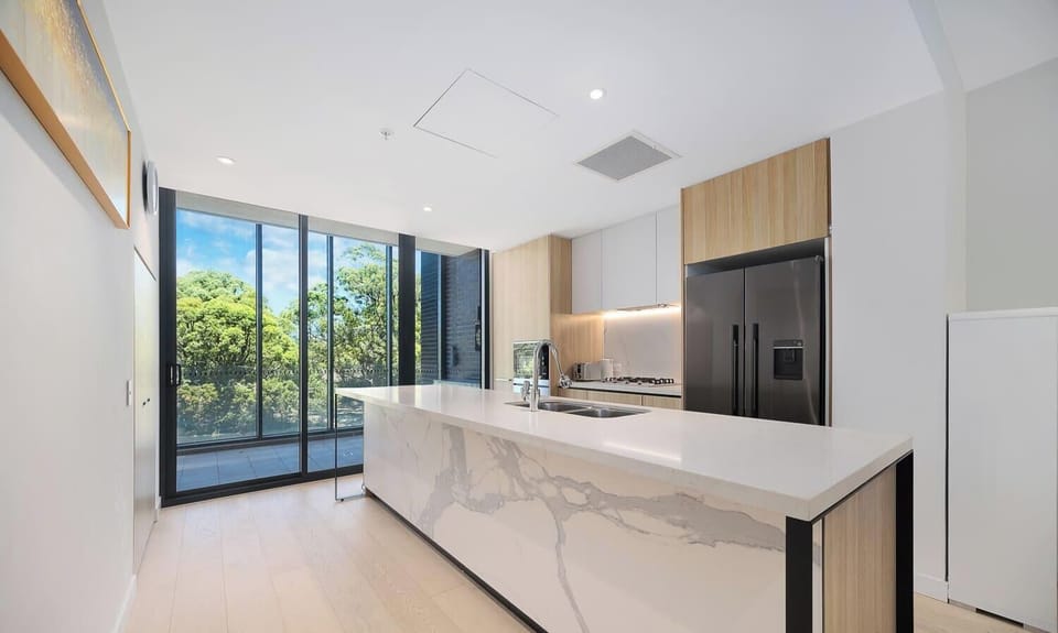 Modern kitchen with island bench, stone countertops, and full cooking facilities.
