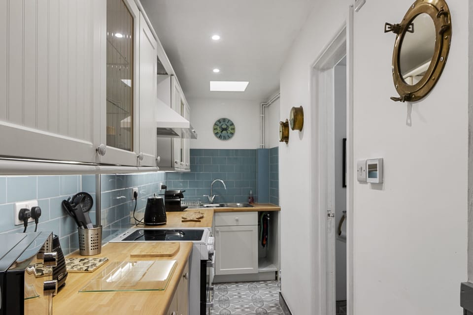 Combining practicality with coastal charm, this kitchen provides all the essentials â€“ oven, hob, washing machine, and coffee machine â€“ complemented by tasteful nautical decor.
