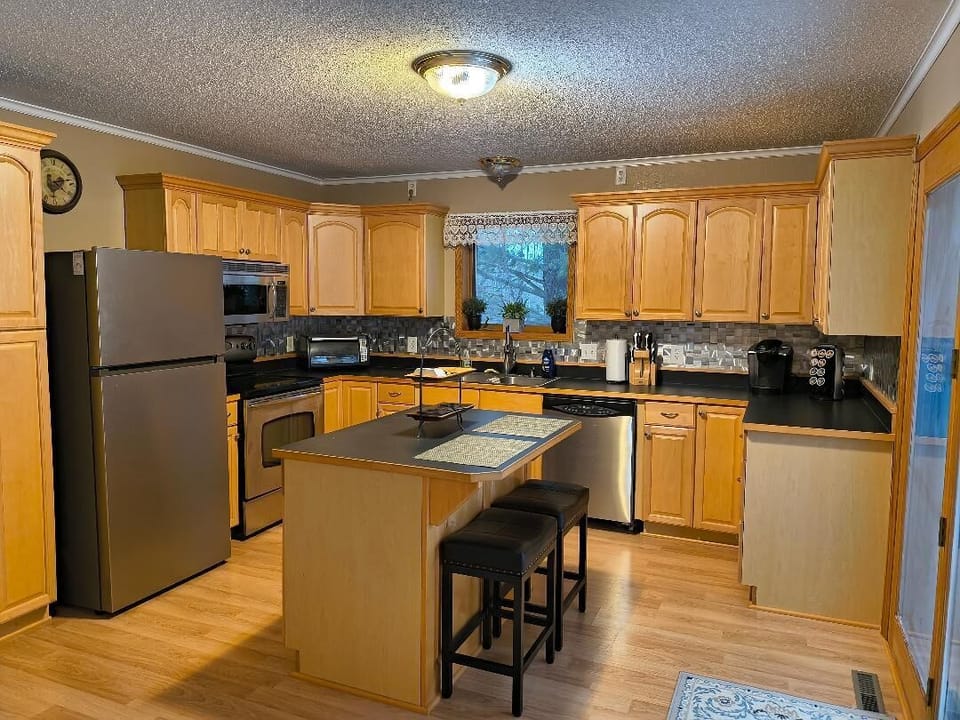 Fully furnished kitchen. Bar stools at center island. 