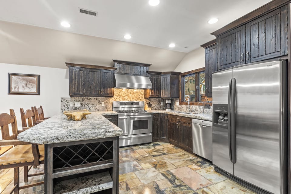 The gourmet kitchen features granite countertops, stainless steel appliances, and rustic cabinetry.