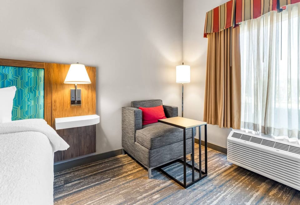Unwind in a bright room with cozy chair and lamp.