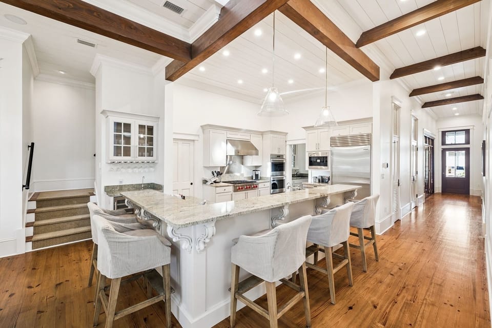Your gourmet kitchen features elegant white cabinetry, marble countertops, and exposed wood beams creating a perfect space for memorable meals.