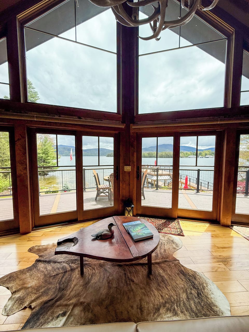 The living room features expansive windows framing a picturesque view. 