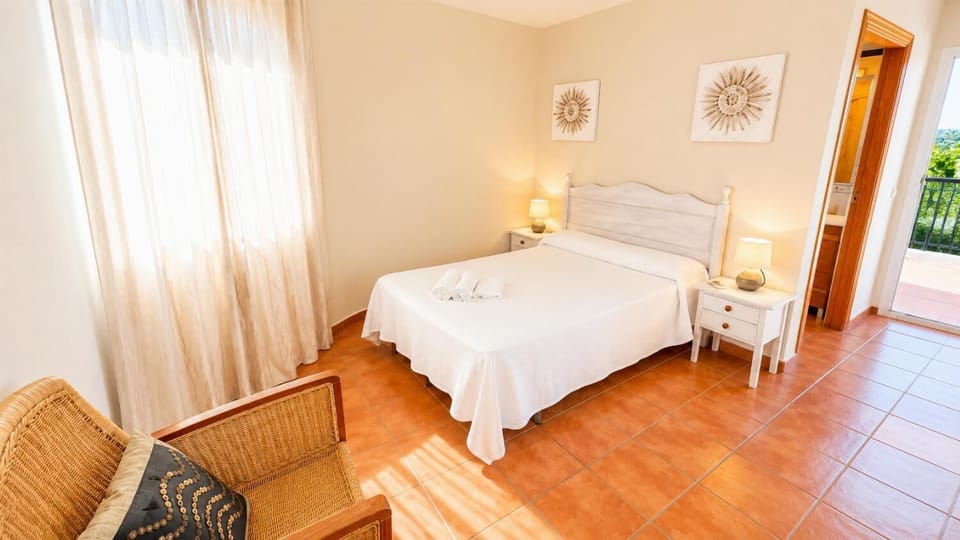 Cozy villa bedroom with terracotta flooring and balcony access.