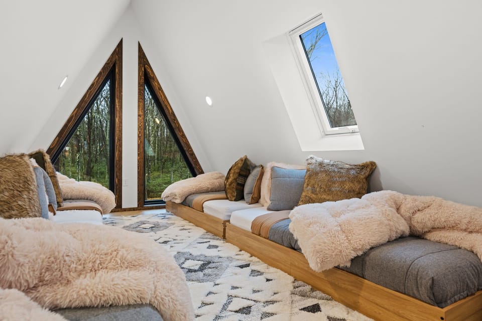 Treetop loft retreat with cozy daybeds and sweeping forest views through A-frame windows
