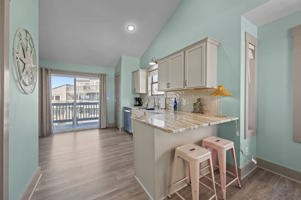 Bright coastal kitchen featuring a breakfast bar with seating and easy access to the balcony—perfect for quick meals and morning coffee