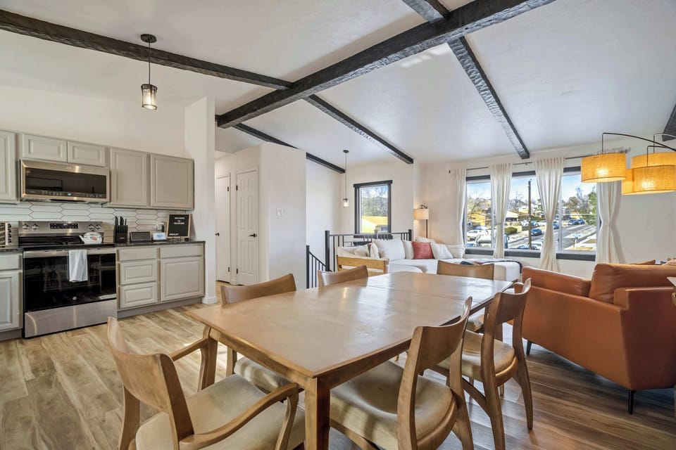 The central dining area features a large wood table with seating for the whole group. Located right off the kitchen, it is the perfect spot for shared meals or evening board games.