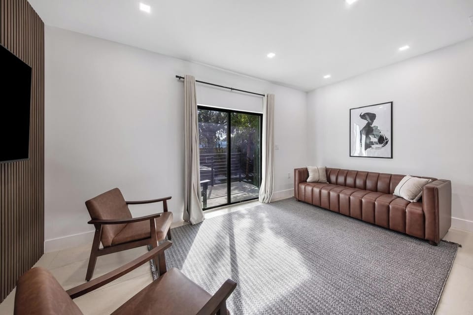 Modern living room with leather seating and natural light from sliding glass doors.