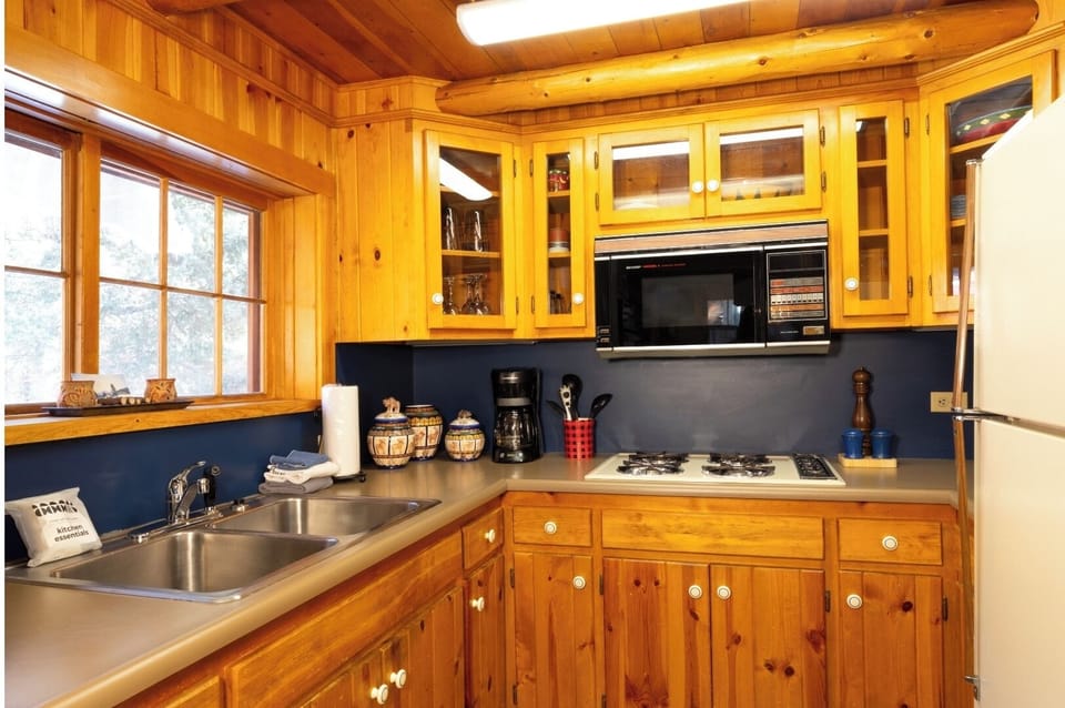 Picture yourself preparing meals in this charming wooden kitchen, with natural light streaming through the windows and all the essentials at your fingertips for a cozy home-away-from-home experience.