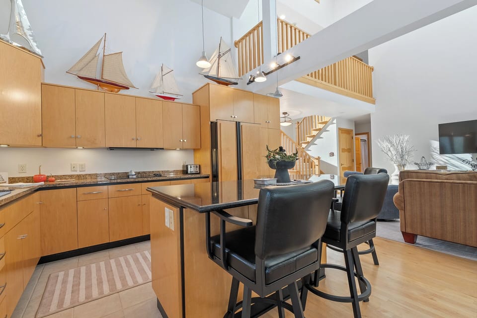 Your stylish loft kitchen invites culinary adventures with sleek granite counters and nautical touches under soaring ceilings.