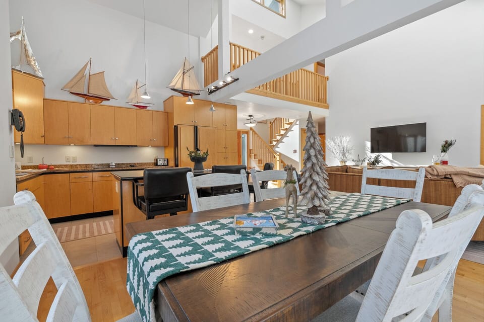 Your spacious open-concept living area features soaring ceilings, warm wood accents, and nautical charm with model sailboats overhead.