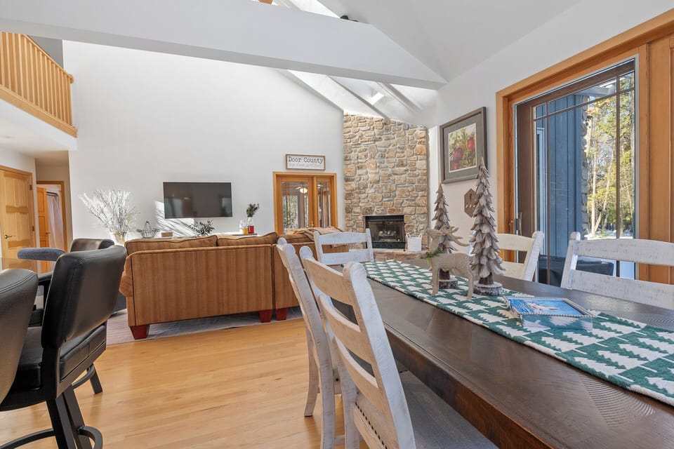 Relax in your spacious open-concept living space with vaulted ceilings, stone fireplace, and large windows framing forest views.
