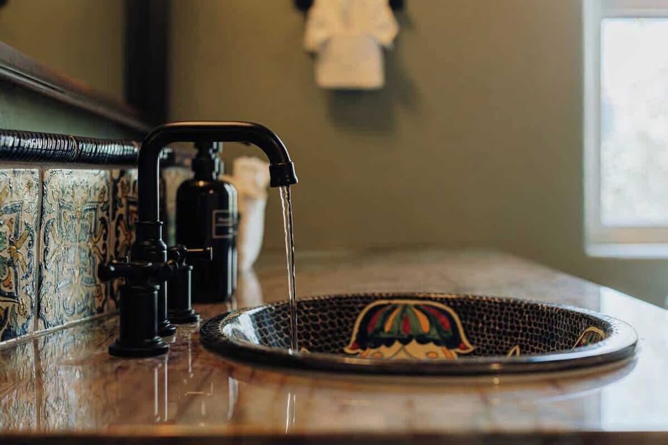 Discover your beautifully appointed bathroom featuring an elegant painted ceramic sink with intricate patterns and modern fixtures for a unique, luxurious experience.