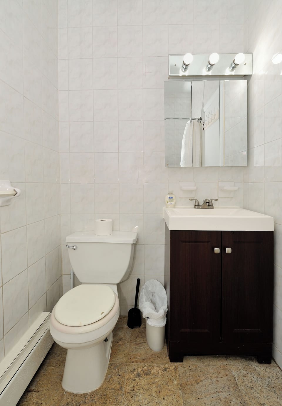 Your private bathroom features modern fixtures with a sleek vanity, mirror with lighting, and fresh white tiles throughout.