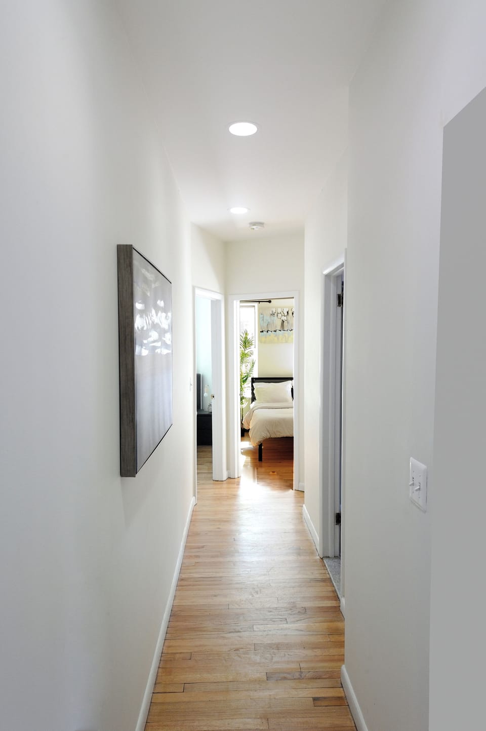 Step through this bright hallway where warm hardwood floors lead you to your peaceful bedroom retreat.