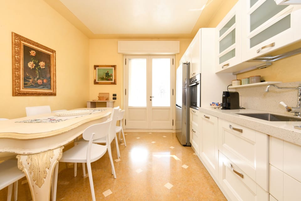 Refined and bright kitchen of Villa Bugatti, with decorated table and artwork. An elegant and welcoming space for special moments on Lake Garda.
