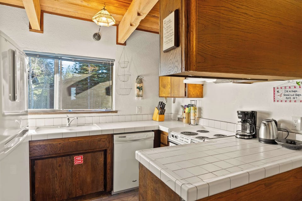 Fully equipped kitchen with tiled counters, white appliances, and a morning coffee station.