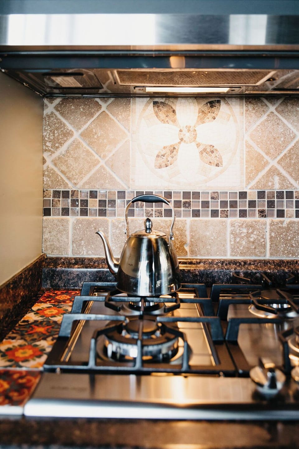 Sleek gas range with kettle, stone backsplash and granite counters