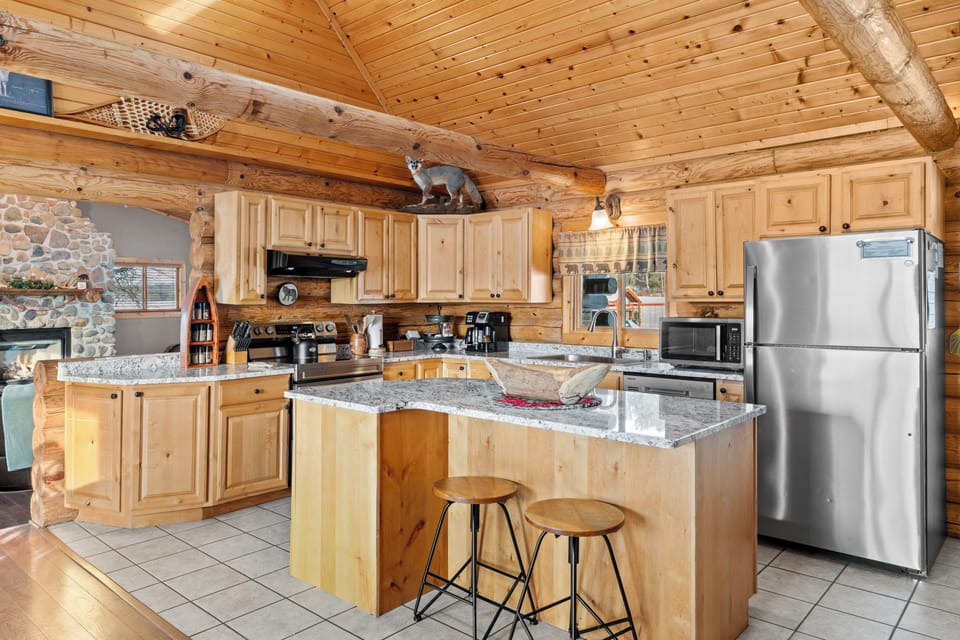 Spacious log kitchen with granite counters, stainless appliances, island seating