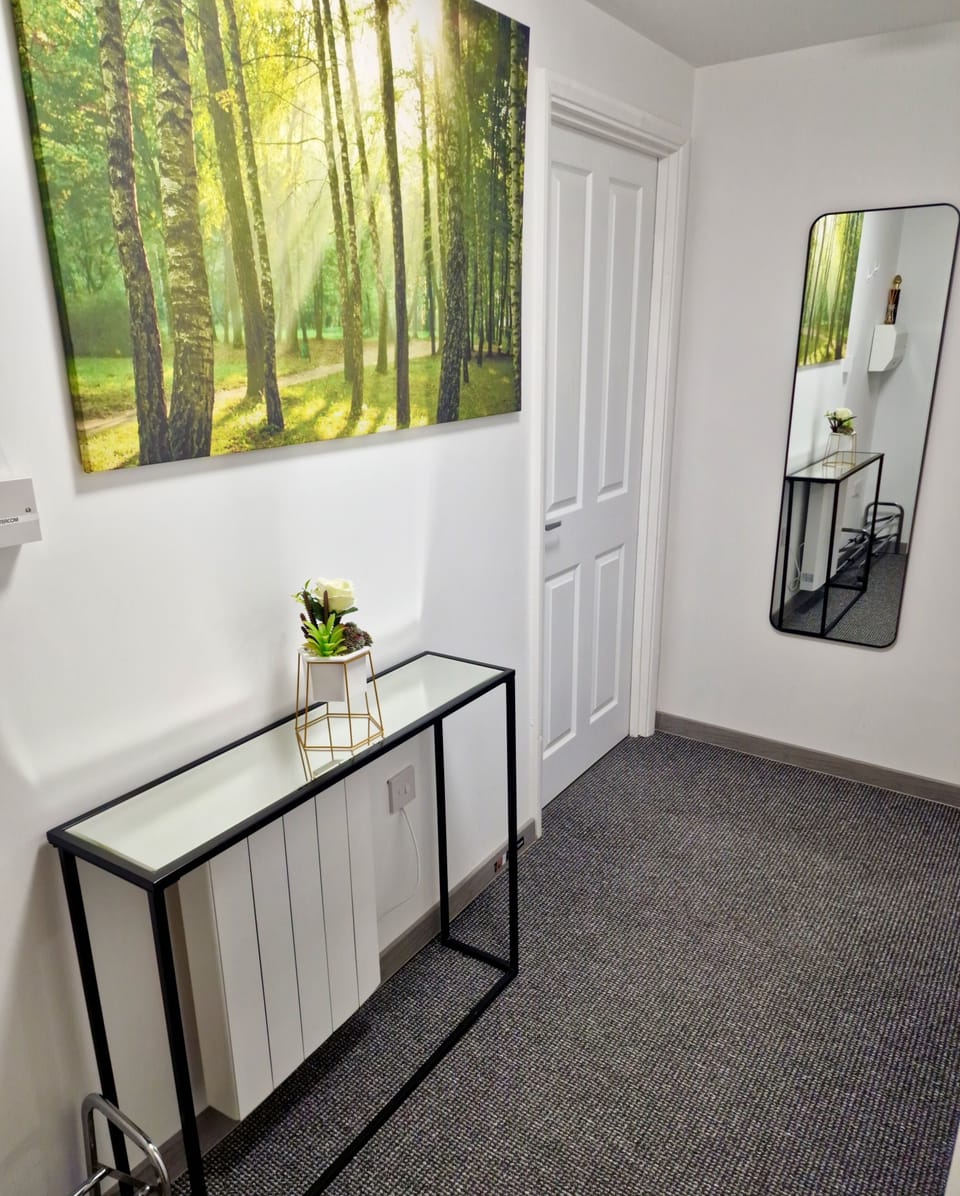 Bright entry with sleek console, full-length mirror, forest art