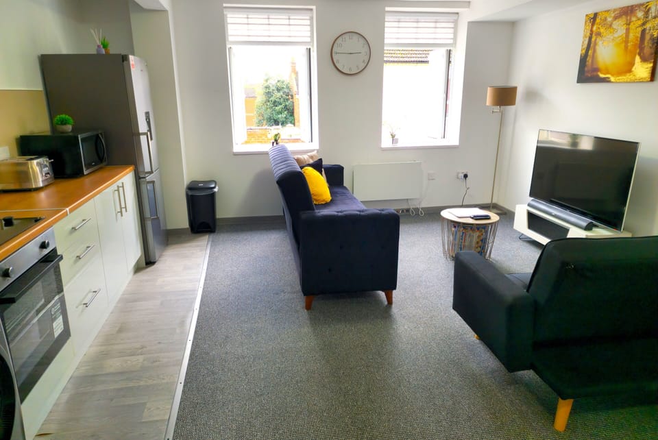 Sunny open-plan lounge with full kitchen, comfy seating and large TV.