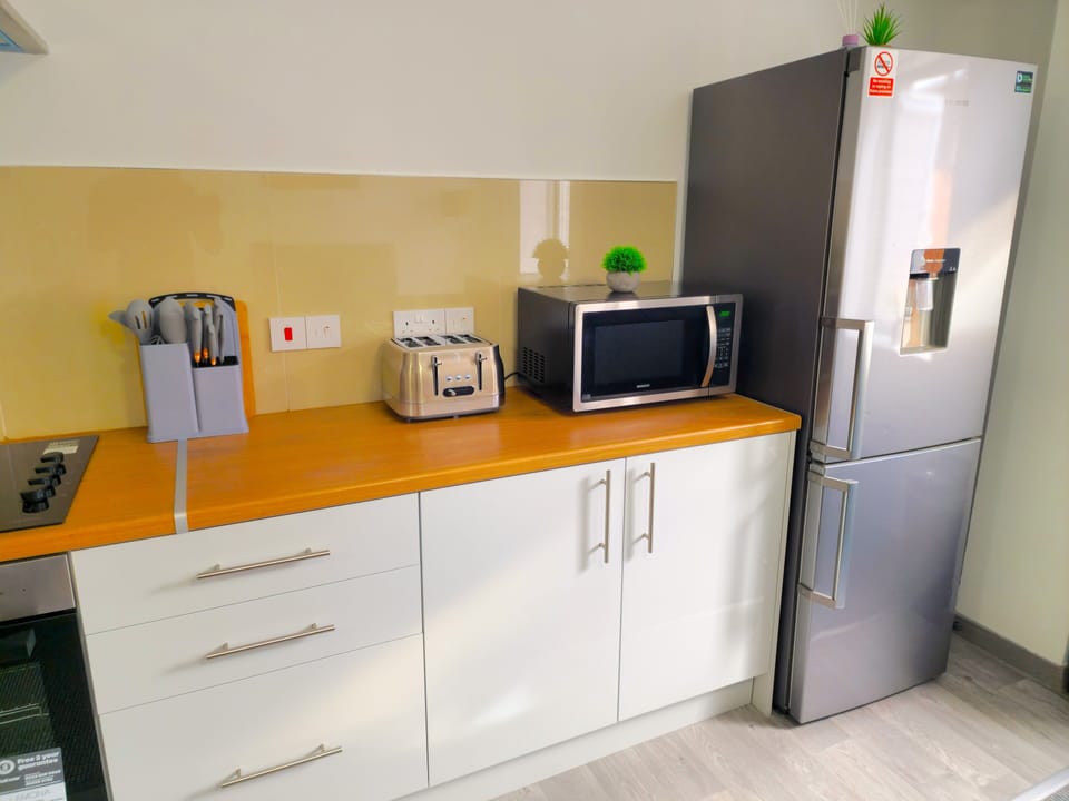 Modern kitchen: full-size fridge, microwave, toaster, and cooktop