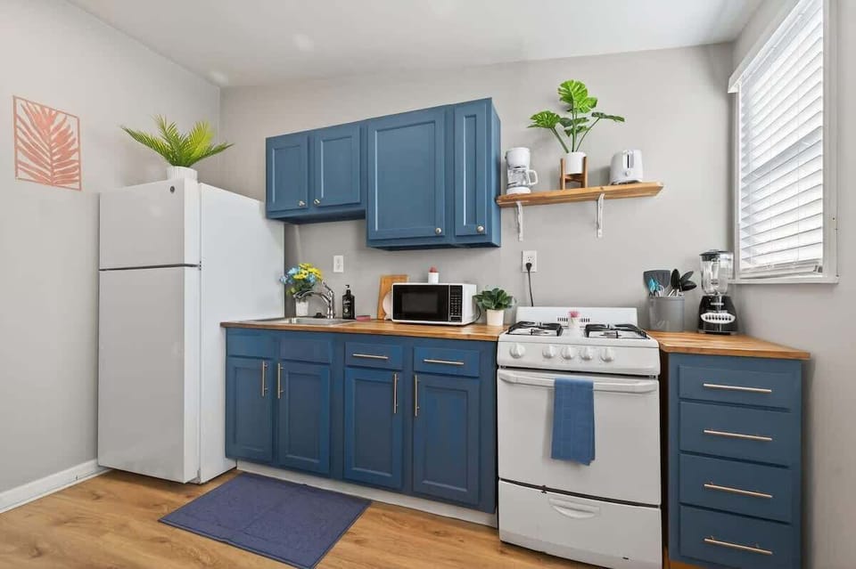 This compact kitchen offers bold blue cabinetry and essential appliances. Bright accents and open shelving make the space feel cheerful and functional. 