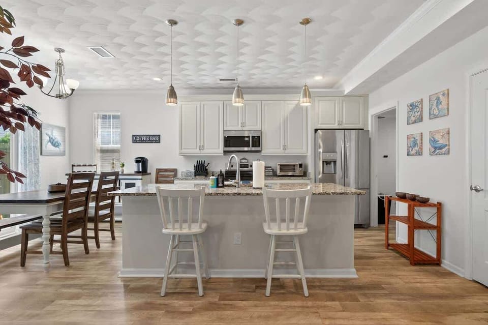 Fully equipped modern kitchen with granite countertops, stainless steel appliances, and a breakfast bar with seating.