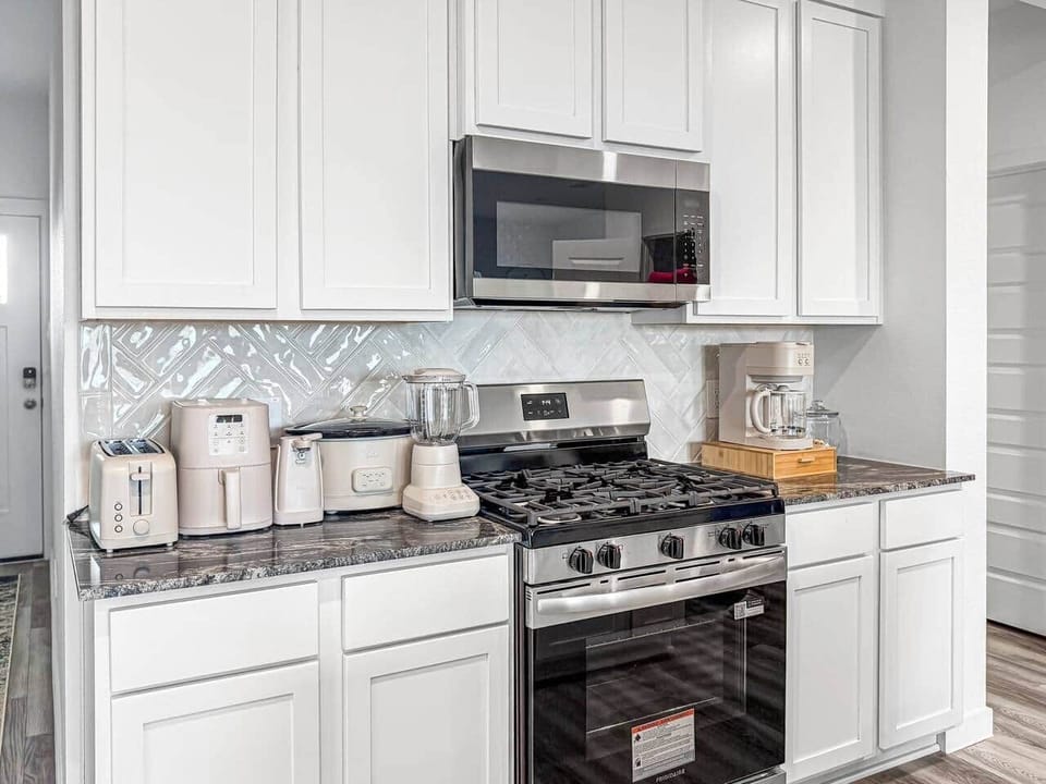 Well-equipped kitchen with everything you need for everyday cooking, including a toaster, air fryer, electric can opener, crock pot, blender, stove, oven, microwave, coffee machine, plus pots, pans, and cooking utensils (not pictured).