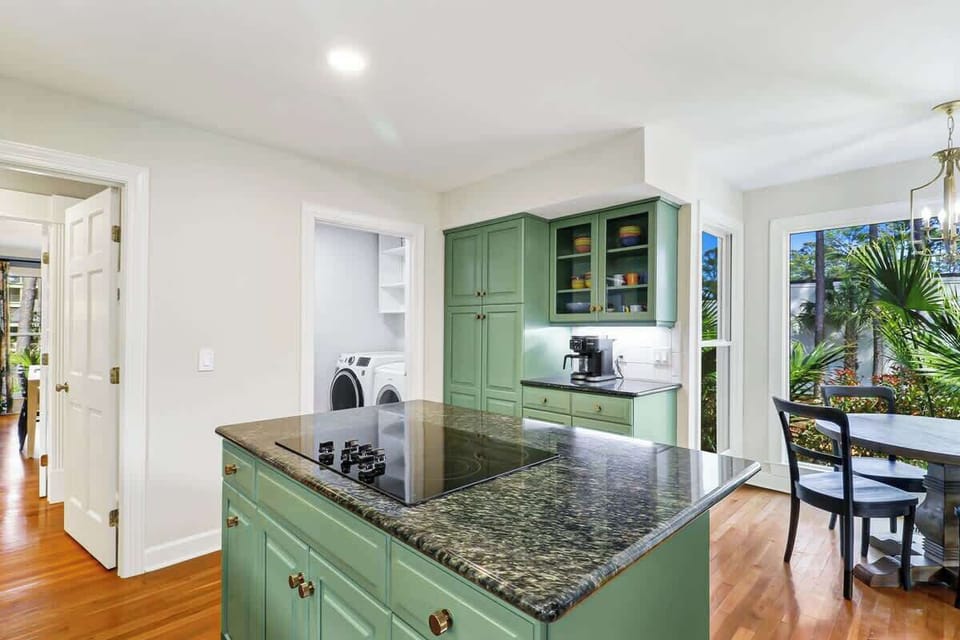 Functional kitchen island with granite counters and sage-green cabinetry creates the perfect space for meal prep and morning coffee.
