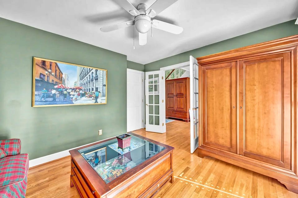 Relax in this charming room with sage-green walls, gleaming hardwood floors, and classic furnishings that create a welcoming atmosphere.