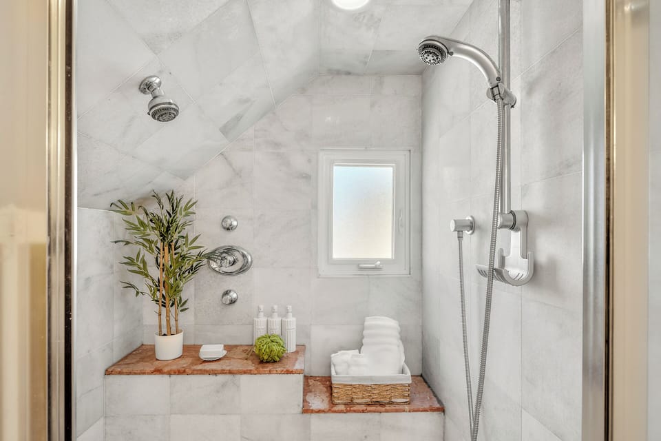 Freshen up in a sleek marble-tiled shower featuring dual showerheads