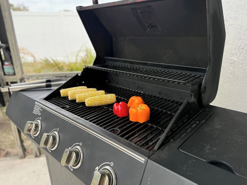 Gas grill sitting on the back patio near the pool area ready to grill an amazing lunch