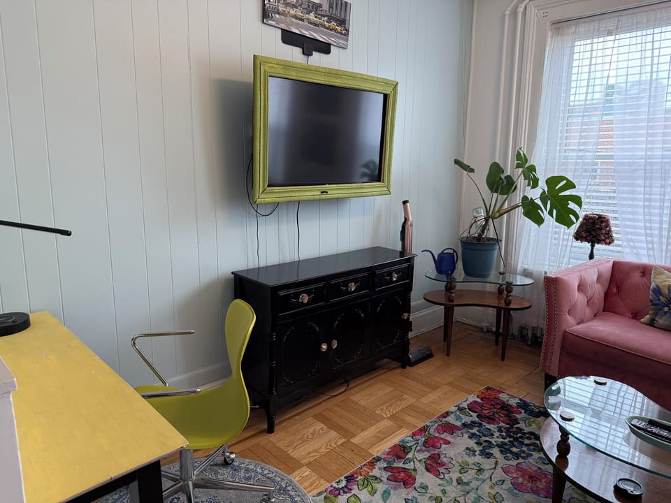 Living room with workspace, couch and natural light with plants