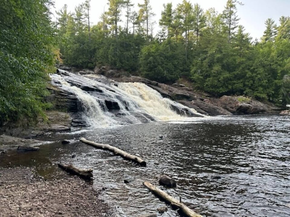 Bright Adirondack-style living room with warm wood accents, comfortable seating, fireplace, and large windows overlooking the 30-acre property. Newly renovated space designed for relaxing after exploring the private cabin’s trails and waterfall.