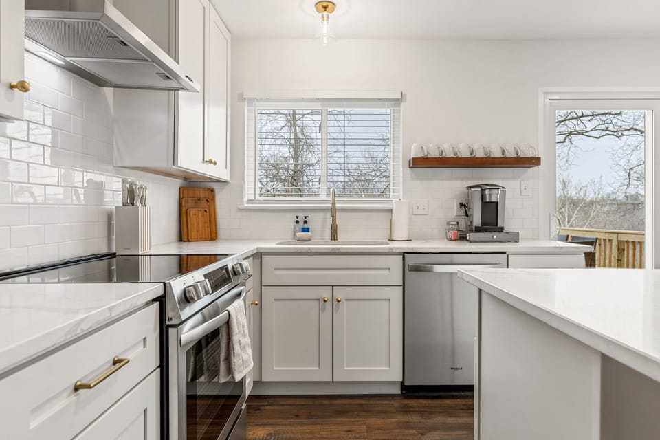 A broad kitchen work area combines abundant cabinetry, counter space, a windowed sink, and full-size appliances.