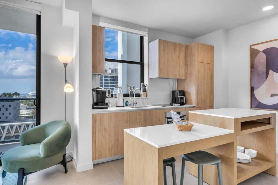 Bright and seamless. Look out from the modern kitchen—featuring quartz countertops and a glass cooktop—straight through to the sun-filled living room and balcony beyond
