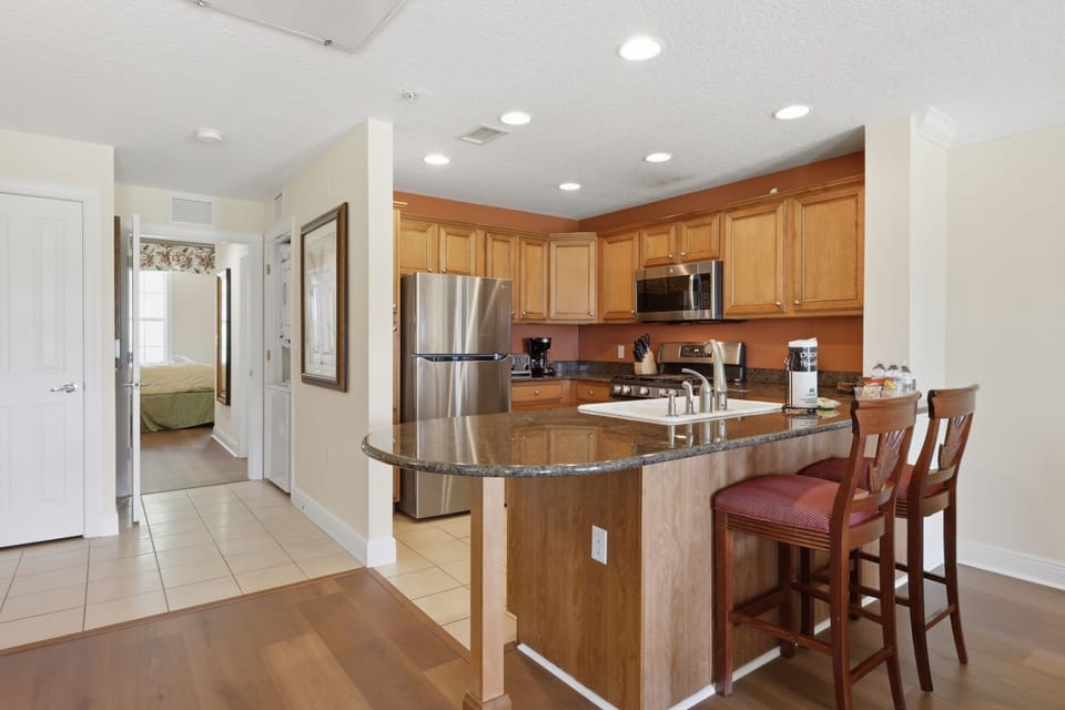 The open kitchen includes generous counter space and bar seating, making it easy to serve breakfast or chat while dinner is prepared.