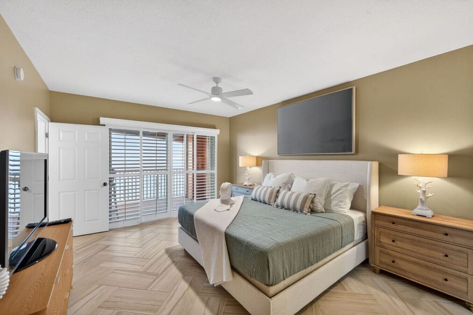 Bedroom w/ cozy seating, TV & sliding doors letting in plenty of natural light.