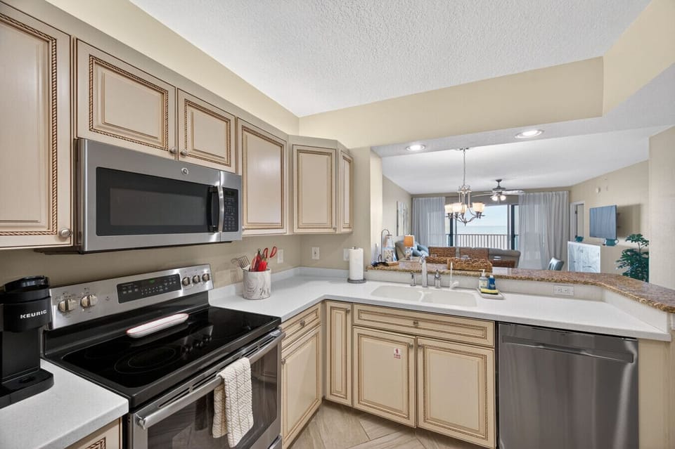 Fully equipped kitchen w/ ample counter space, cabinetry & breakfast bar seating.
