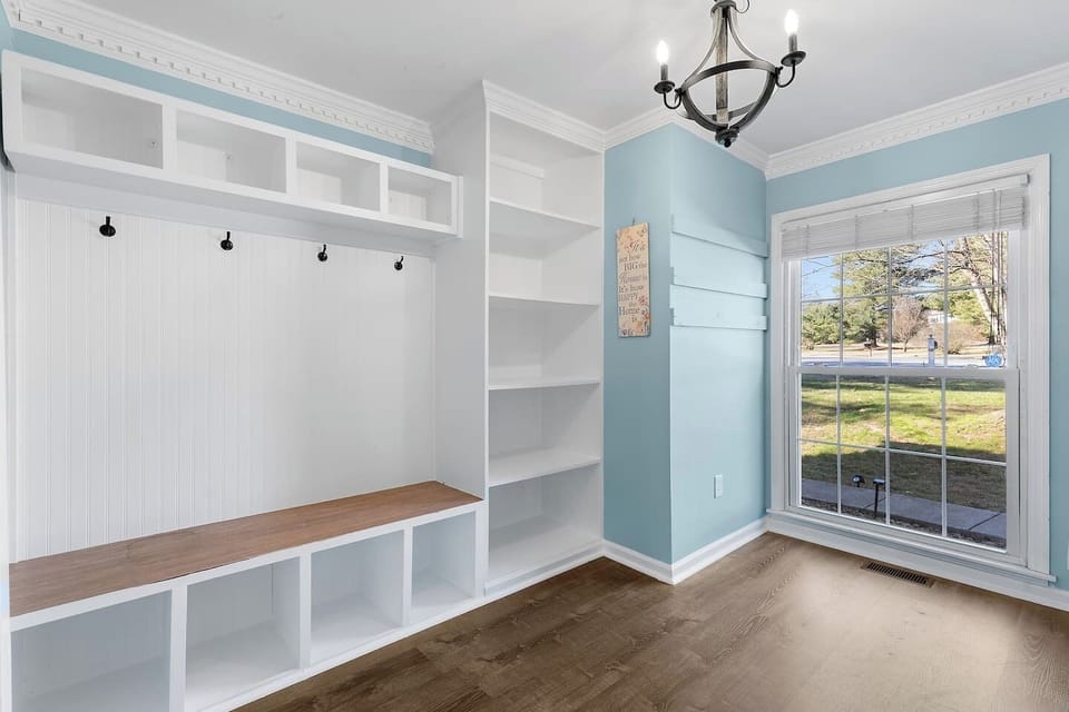 Spacious laundry room with full-size washer and dryer, built-in shelving, dog washing station, folding counter, and storage cubbies.