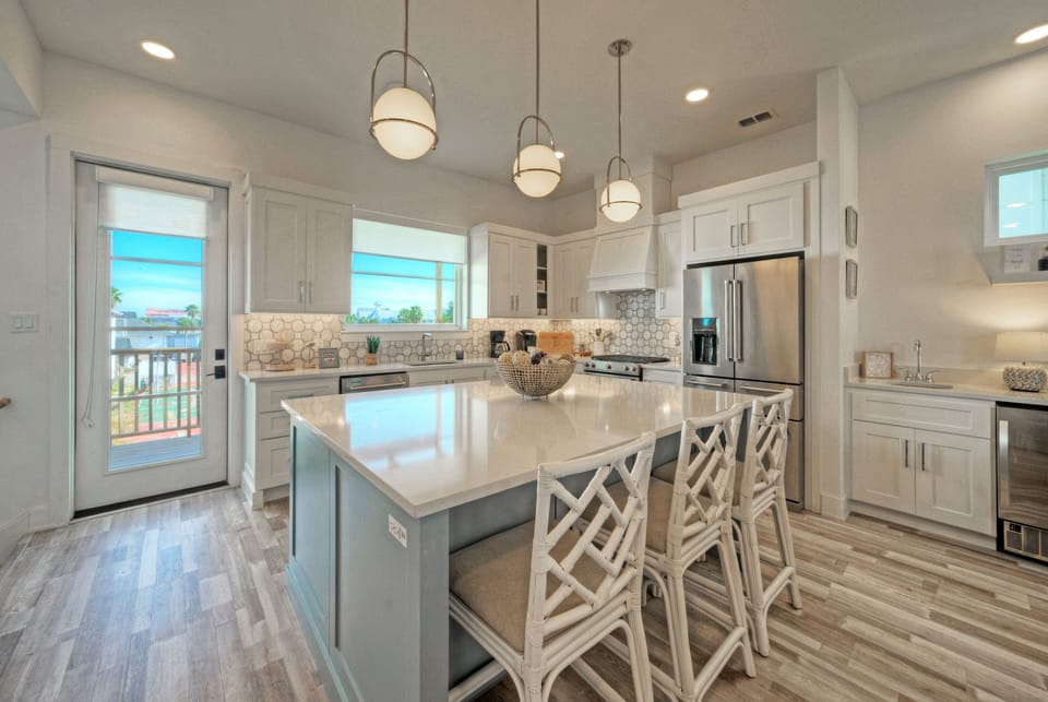 Open-concept kitchen with island, white cabinetry, and hanging pendant lights.