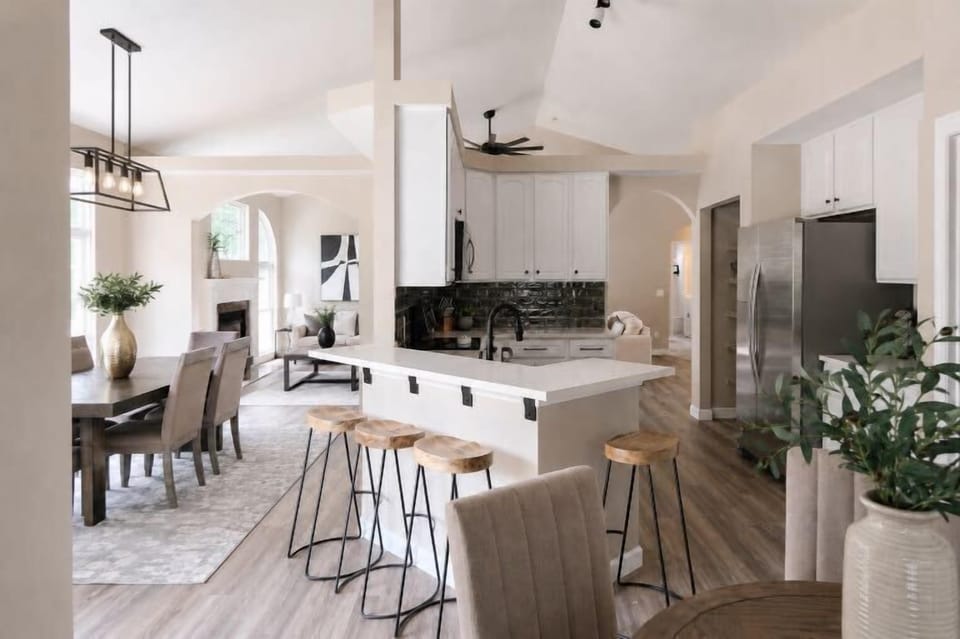 The open kitchen combines a breakfast nook, waterfall-edge island, bar stools, and an easy connection to the dining room.