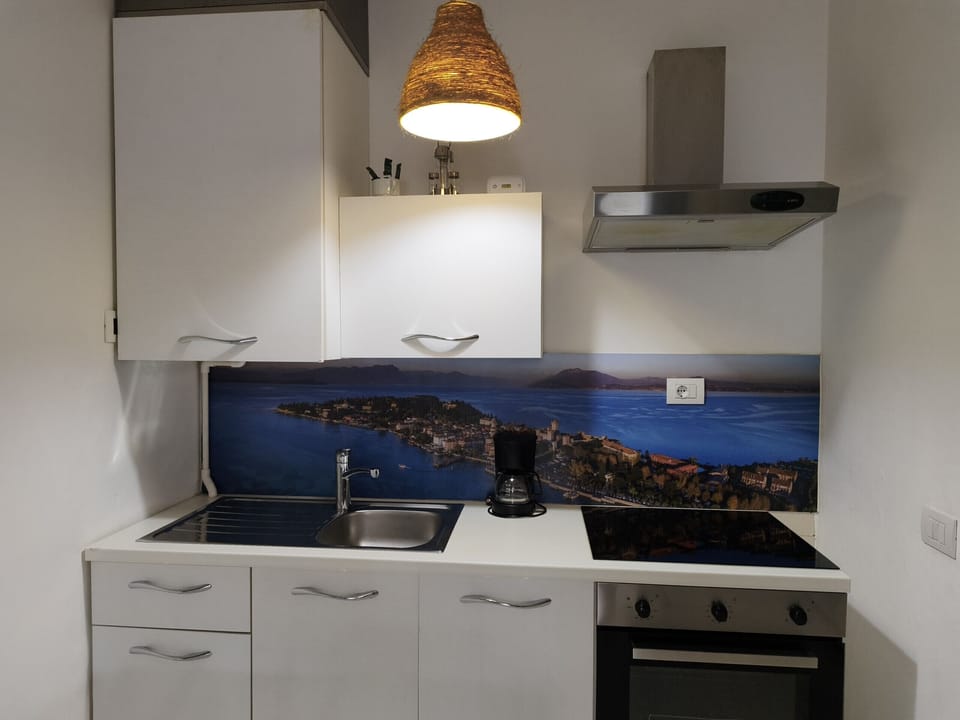 Kitchen in the apartment located in the center of Sirmione, fully equipped and functional. The space has a stove, oven, sink, extractor hood, and storage cabinets, ideal for preparing meals independently during your stay.