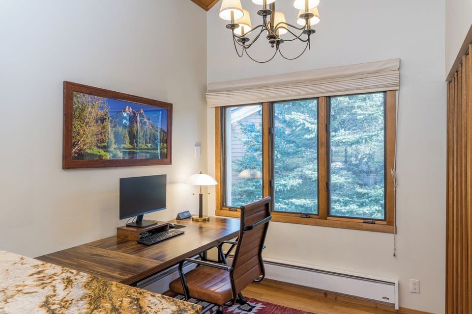 Stay productive in your private workspace, complete with a computer, surrounded by warm wood accents and peaceful mountain views.