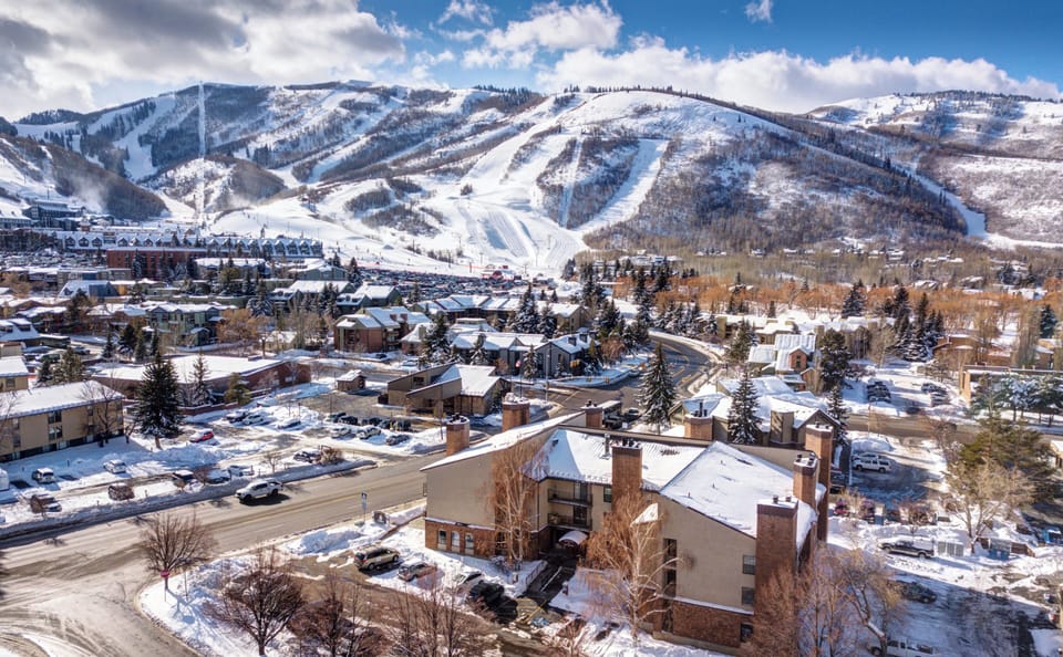Snow-covered ski resort town nestled beneath pristine mountain slopes, with ski runs carved into the winter landscape and cozy lodges dotting the valley below.