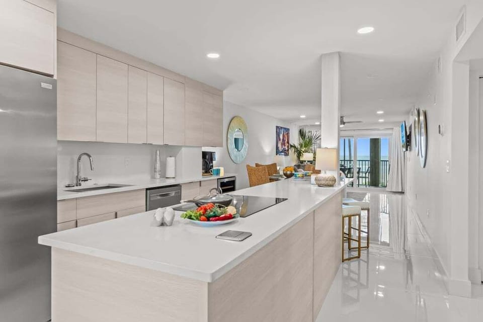 Experience effortless coastal living at Riviera Club 102 — an open-concept kitchen, dining, and living space seamlessly extends to the lanai, showcasing sweeping Gulf-front views.