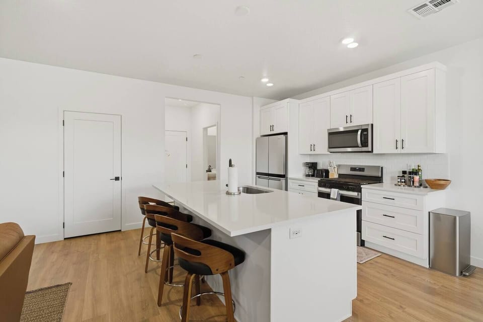 Modern open kitchen with large island, bar seating, and stainless steel appliances.